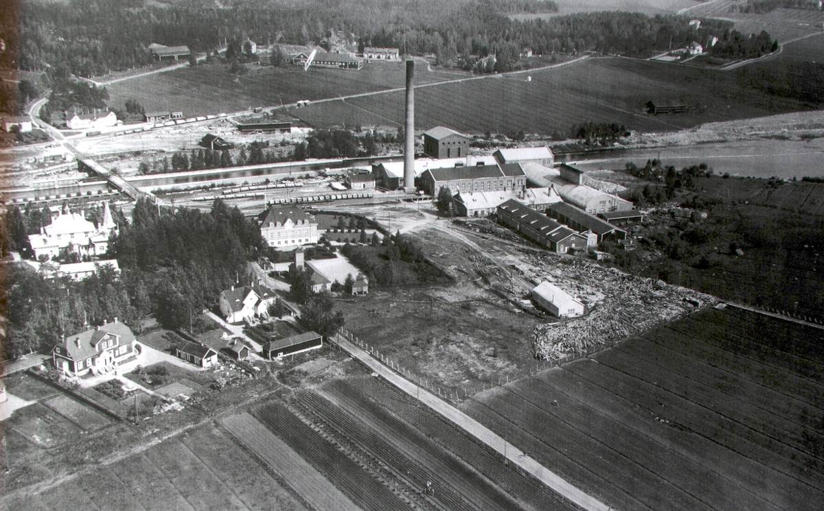 Tehdasaluetta ja koskiuoman itäpuolisia alueita 1930-luvun alkupuolelta. Äänekoski-Suolahti maantie kulki ennen Hiskinmäen sillan valmistumista tehdasalueen, entisen rautatieaseman eli Tenttukerhon ja Hiskinmäen koulun ohitse. Heti pitkän piipun vasemmalla puolella näkyy Mannilan talo.