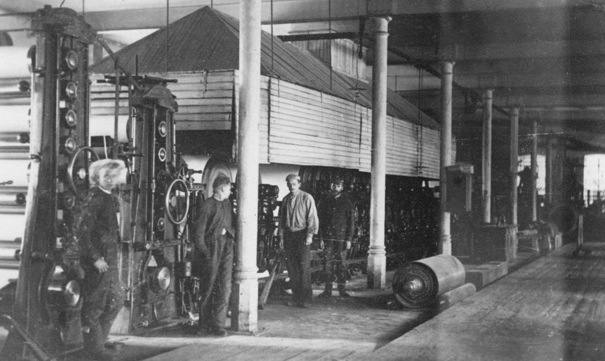 Vanhan kartonkitehtaan konesalia kuivastapäästä märkäänpäähän päin vuodelta 1902. Kone oli toiminnassa Äänekoskella kaikkiaan yli 70-vuotta alkaen vuoden 1899 alusta aina pysäyttämiseensä 17.5.1969 saakka. Koneen työleveys oli noin 1600 mm ja maksiminopeus 35 m/min. Puuhiomot sijaitsivat kuvan oikeassa reunassa konesalin virranpuoleisella seinällä ja tehokas ketjinkihiomo puolestaan oli sijoitettu konesalin pohjoispäähän kuvan takaseinälle. Kuivausosan päällä on mielenkiintoisen näköinen lautarakenteinen huuva. Käytävällä on ilmeisesti kuivausosaan kuuluva sylinteri varastoituna. Vanhan kartonkikoneen konesali oli myöhemmin paperitehtaan käytössä vuoteen 2010 saakka erilaisten koneenosien varastona.