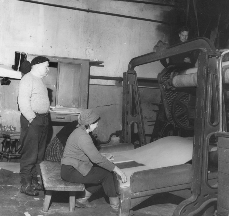 Vanhan kartonkikoneen kuivanpään arkkileikkuri ja sen henkilökuntaa 1960-luvulla. Takana seisoo kartonkikoneen pitkäaikainen koneenhoitaja Yrjö Hirvi. Arkkeja vastanottamassa Maija Hokkanen. Toinen nainen on tuntematon. Leikkurin takana työssä Lassi Hakulinen. Ilmeisestikin koneen koko lähes koko tuotanto arkitettiin suoraan kartonkikoneen linjan päässä olevalla arkkileikkurilla ja lajiteltiin sekä pakattiin kerrosta ylemmässä olevassa arkkisalissa. Alkuaikojen kartonkipaaleilla oli painoa tiettävästi noin 200-225 kg