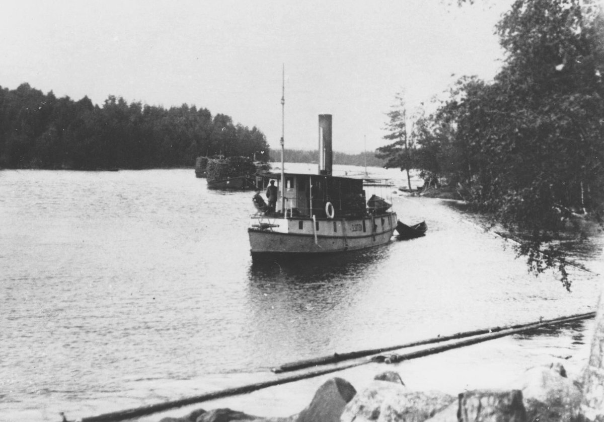 Keitele-höyrylaiva vetää halkolastissa olevia proomuja.