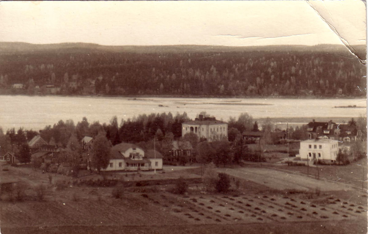 Etualalla Eerolan talo ja heti sen oikealla puolella Kankaisen talo, jonka takana näkyy vanha 1928 valmistunut sairaala ja sen oikealla puolella valkoinen vuonna 1948 valmistunut kunnanlääkärin talo. Kuvan vasemmassa reunassa 1961 vanhainkodin tieltä purettu kulkutautisairaala ja sen edessä Eerolan navetta, jossa toimi myöhemmin Ammulaksi kutsuttu elokuvateatteri. Eerolan talon takaa näkyy kolme pitkää kuusi-puuta, joiden nimet olivat Selma, Kustaa ja Ilmari.