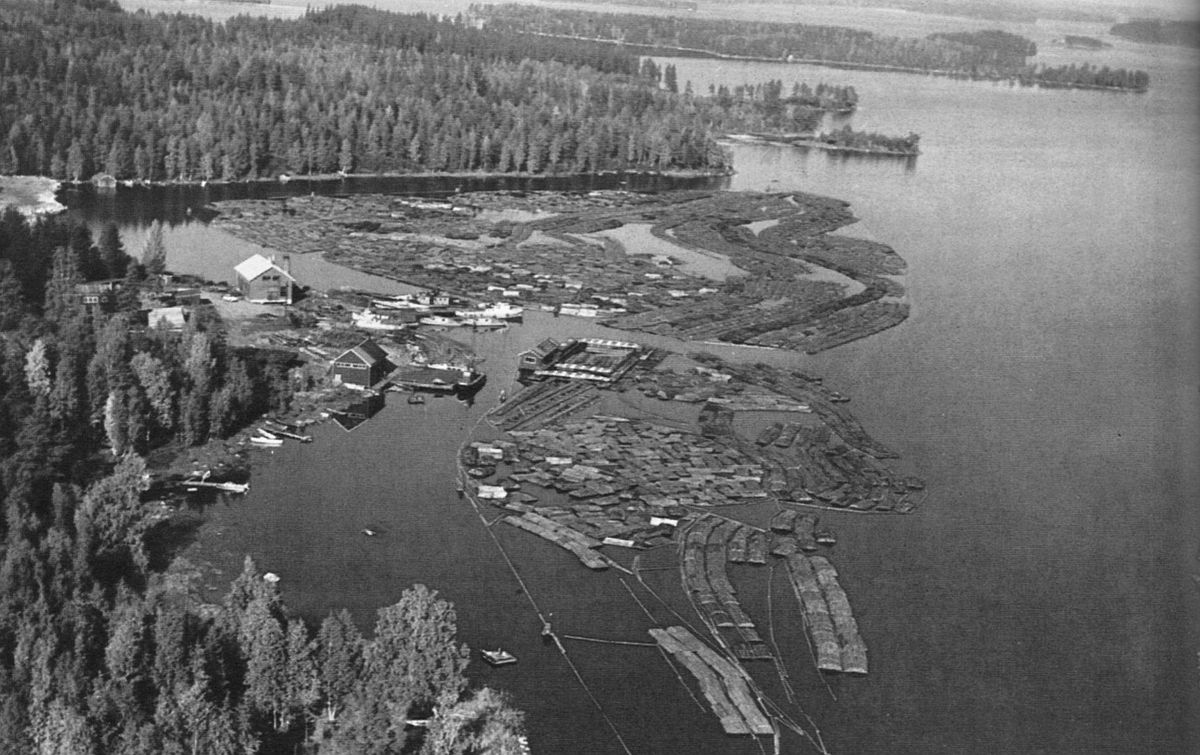 Mustaniemen sataman seutua ehkä 1960-luvulla. Kuvassa keskellä niputuslaite, jota käyttäen uittamalla tuodut puut niputettiin varastointia ja tehtaalle kuljetusta varten.