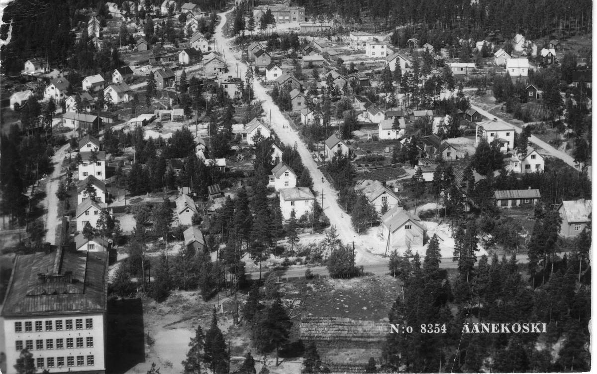 Koulunmäkeä ja Pitkäkatua pohjoiseen. Kuva on otettu vuonna 1952. Kansakoulurakennuksen itäpuolella näkyy suuri halkolaani, jolle vuonna 1957 valmistui koulunmäen laajennusosa. Halkoja käytettiin alkuaikoina Koulurakennuksen lämmittämiseen. Koulun alakerroksessa oli suuri puulämmitteinen uuni, jolla tuotettiin lämmintä vettä rakennuksen lämmittämiseen ja vesihuoltoon.