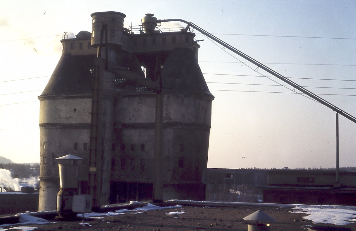 Sulfiitin happotorni. Aiemmin tehtaan tarvitsema puuraaka-aine kuorittiin hiomon ja sulfiitin yhteisellä kuorimolla, jonka yhteydessä olevalla hakulla tukit haketettiin ja nostettiin happotorniin tornin keskellä olevan lokerokuljettimen avulla. Uusi keskuskuorimo tehtaalle valmistui 1973. Tämän jälkeen sulfiitin tarvitsema puuraaka-aine saatiin sieltä valmiiksi haketettuna. Tätä varten rakennettiin kuvassa näkyvä puhalluslinja keskuskuorimolta happotornin katolle.