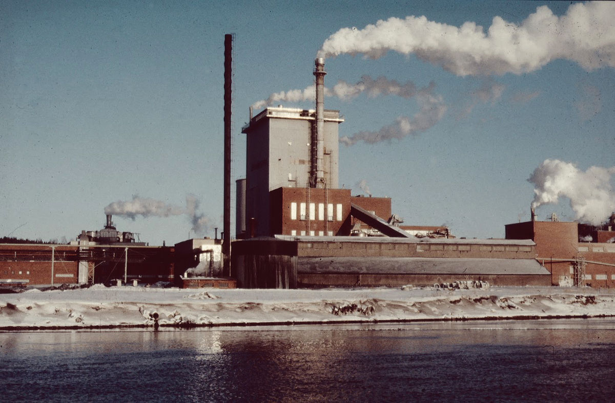 Sulfaattisellutehdasta. Oikealla kuivauskone ja siitä oikealle soodakattila, haihduttamo sekä valkolipeä- ja meesauuniosasto. Soodakattilan edessä virran rannalla glaubersuolavarasto.