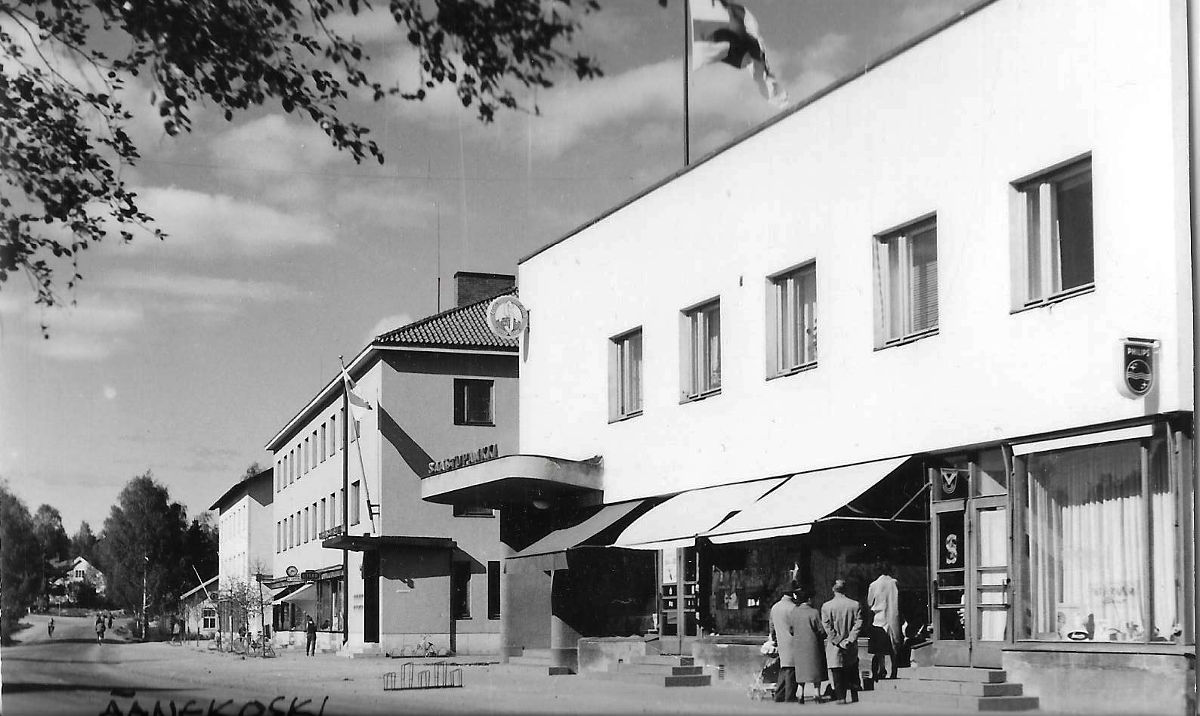 Äänekosken keskustan liikerakennuksia. Etualalla Säästöpankin vuonna 1939 valmistunut rakennus ja sen takana Apran eli apteekin ja rautakaupan vuonna 1952 valmistunut rakennus. Niiden välissä oleva KOP:n talo valmistui vuonna 1950.